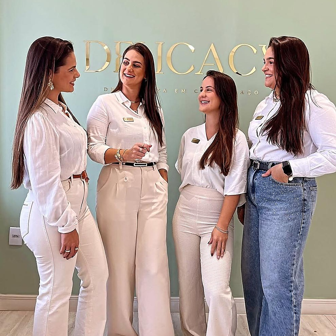 Equipe Delicacy Estética em frente ao logo dourado da clínica em Torres/RS